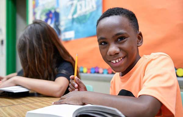 boy in classroom smiling at camera